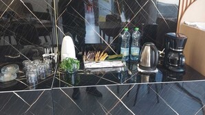 A kitchen counter with a coffee maker, water bottles, and a kettle. - St Barbara Hotel (Bethlehem)