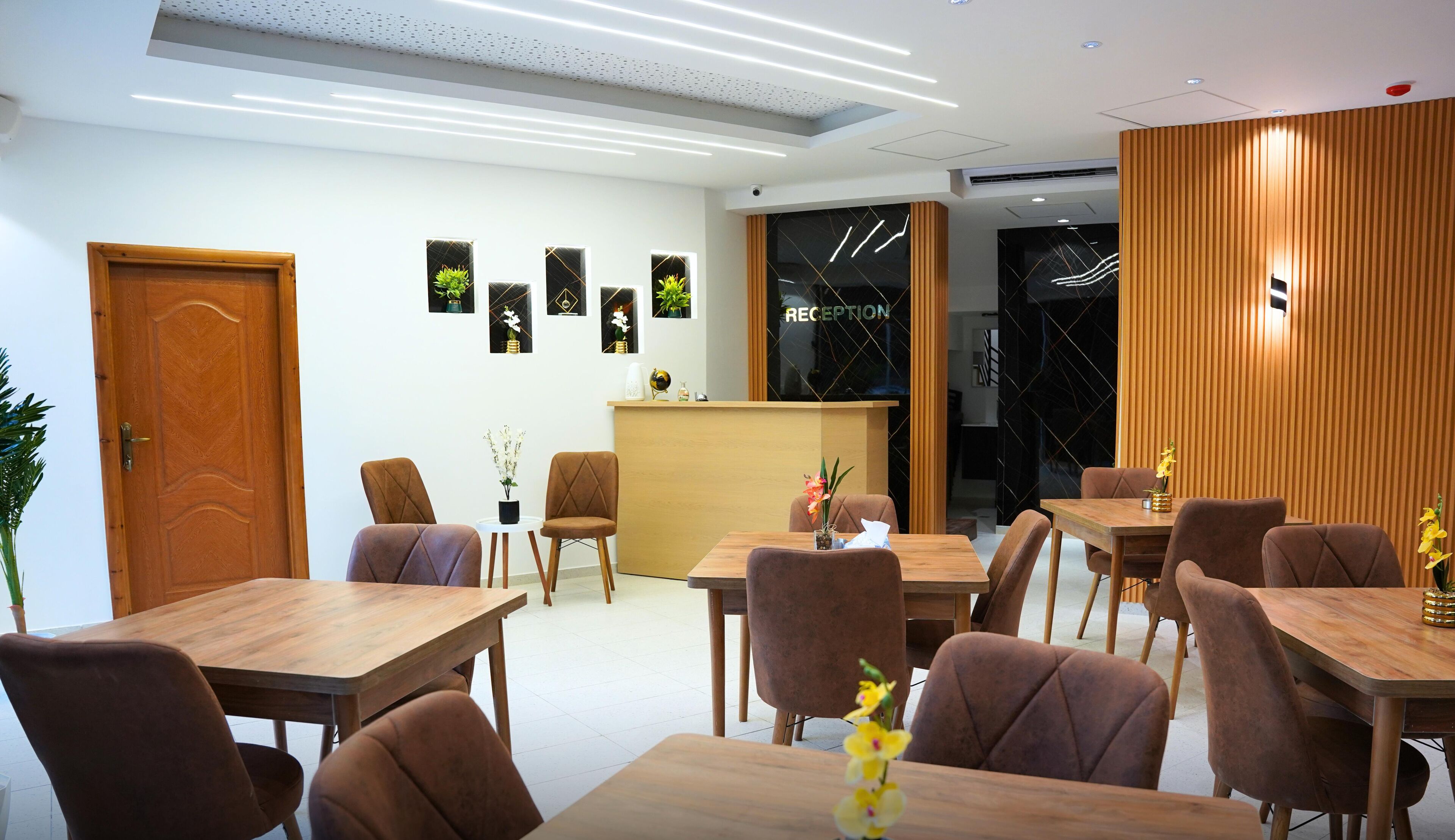 A modern reception area with a wooden reception desk, several brown upholstered chairs, and a reception counter with a glass partition.