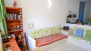 Un salon confortable avec un canapé, une bibliothèque et une petite table sur laquelle sont disposés divers objets.