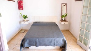 Une chambre à coucher avec un lit, deux tables de chevet, un miroir et une fenêtre.