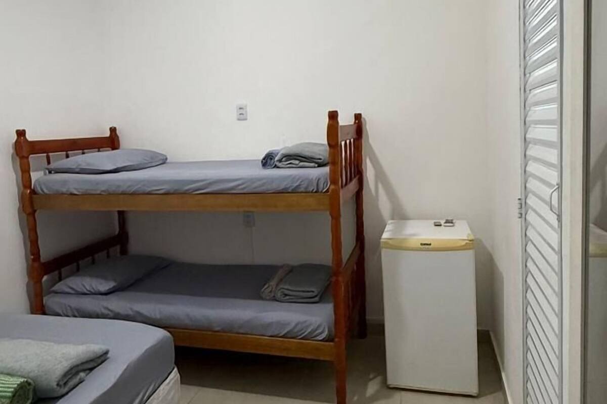 A small, clean room with a bunk bed, a small white cabinet, and a ceiling fan.