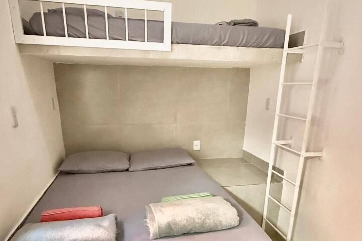 A bunk bed room with a ladder, a window, and a small shelf.