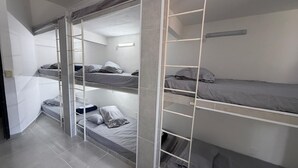 Habitación con literas, una escalera, una lámpara y suelo de baldosas.