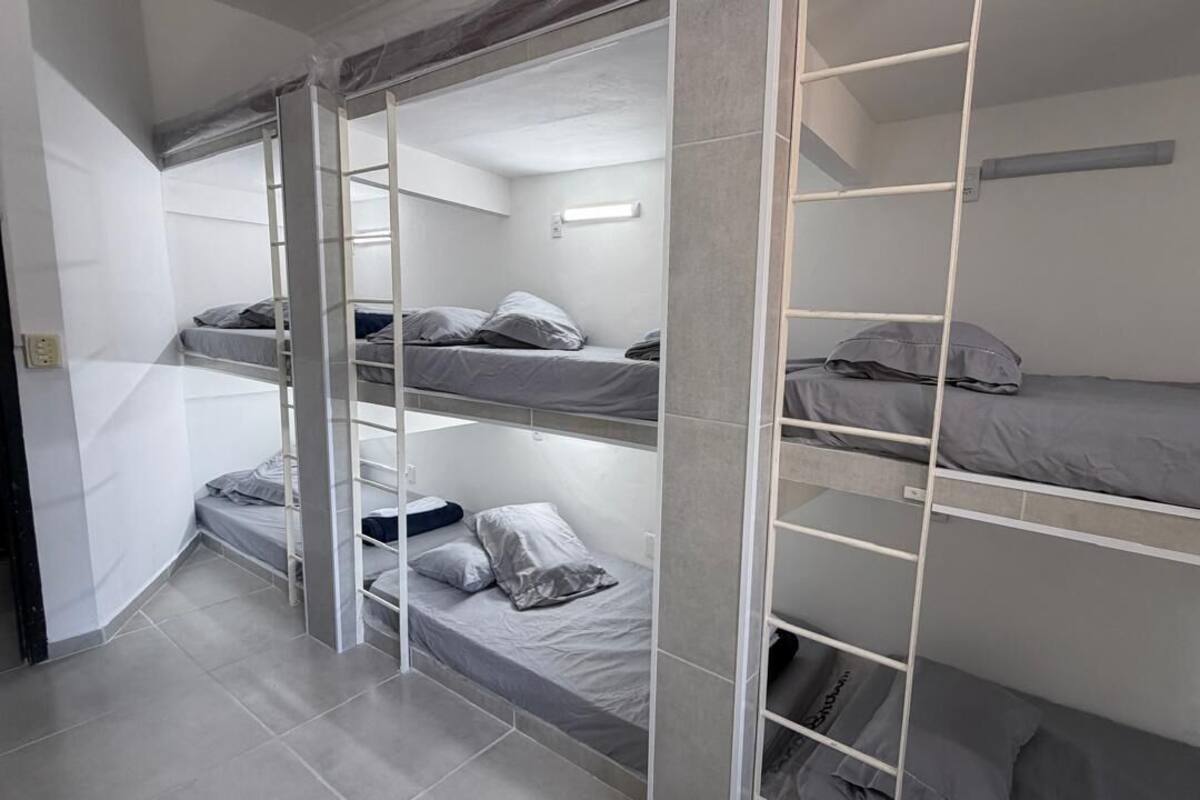 A bunk bed room with a ladder, a light fixture, and a tiled floor.