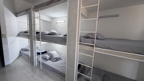 A bunk bed room with a ladder, a light fixture, and a tiled floor.