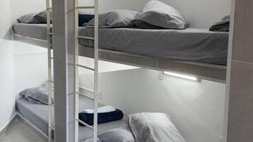 Quarto com beliche e luminária na parede.
