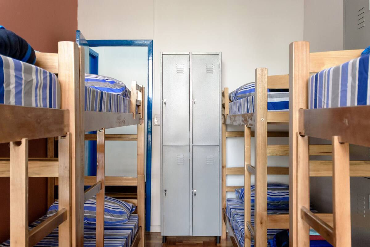 A dormitory room with bunk beds, a wardrobe, and a mirror.