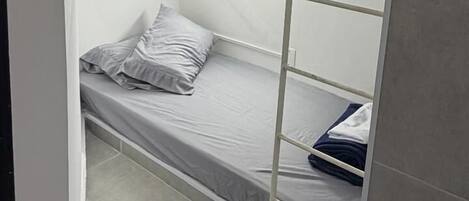 Habitación con literas, una escalera, una lámpara y un enchufe.