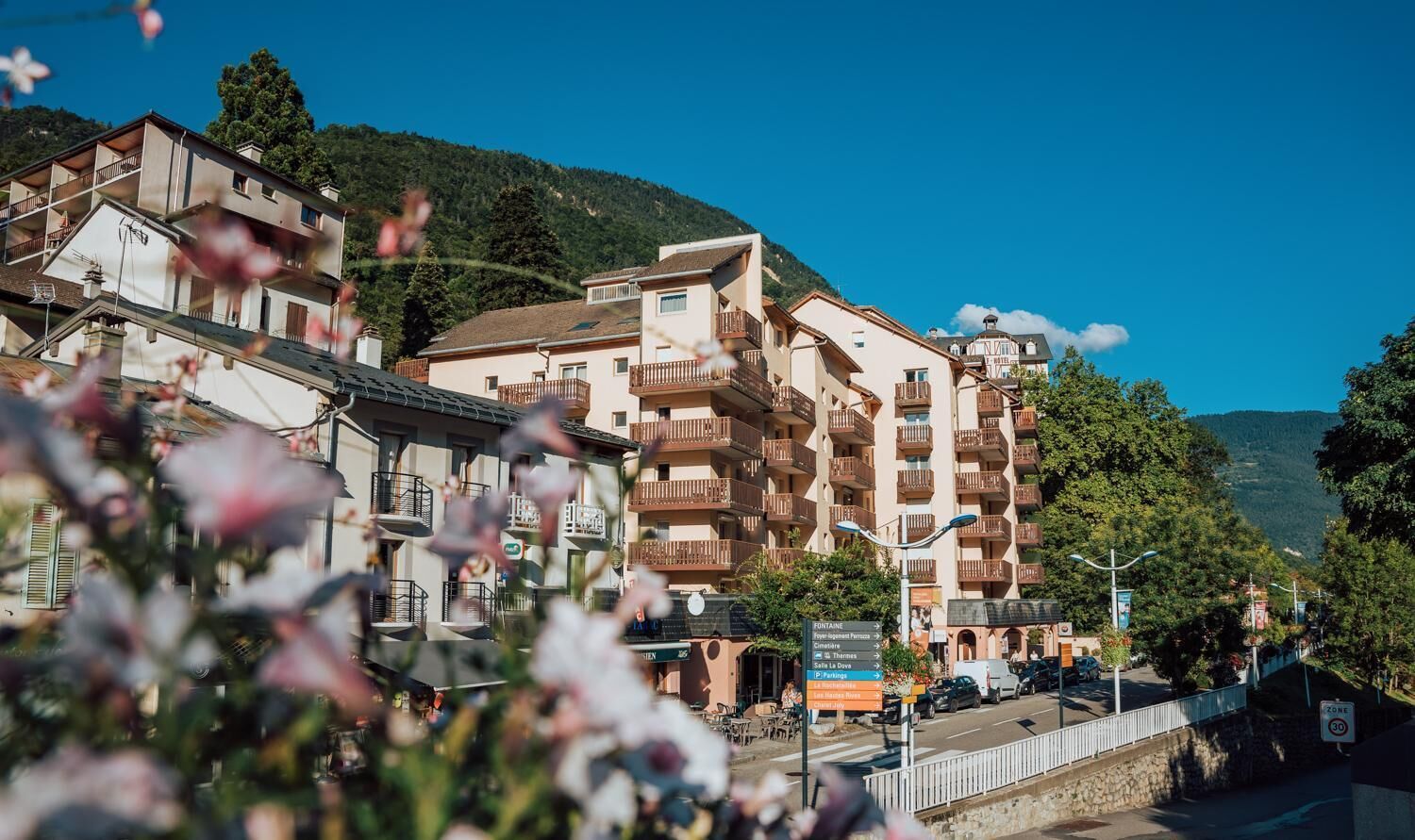 Un hotel de varios pisos con balcones, un cartel con servicios y vistas del entorno.
