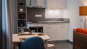 A compact kitchen with a dining area, a built-in bookshelf, and a small table with chairs. - Wifi, resort center, fitness, balcony, tv, 25-32m², Brides Les Bains (Brides-les-Bains)