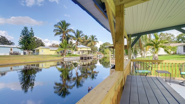 Een houten terras met uitzicht op een rustig waterlichaam en omliggende huizen.