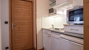 A compact kitchen with white cabinets, a wooden door, a microwave, and a Siemens dishwasher. - Wifi, 200m from ski lifts, fitness, balcony, tv, 31m², Brides Les Bains (Brides-les-Bains)