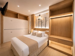 Un dormitorio moderno con cama, mesitas de noche, un armario y un televisor montado en la pared.