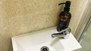 Un lavabo de salle de bain avec un flacon de savon liquide et un robinet.