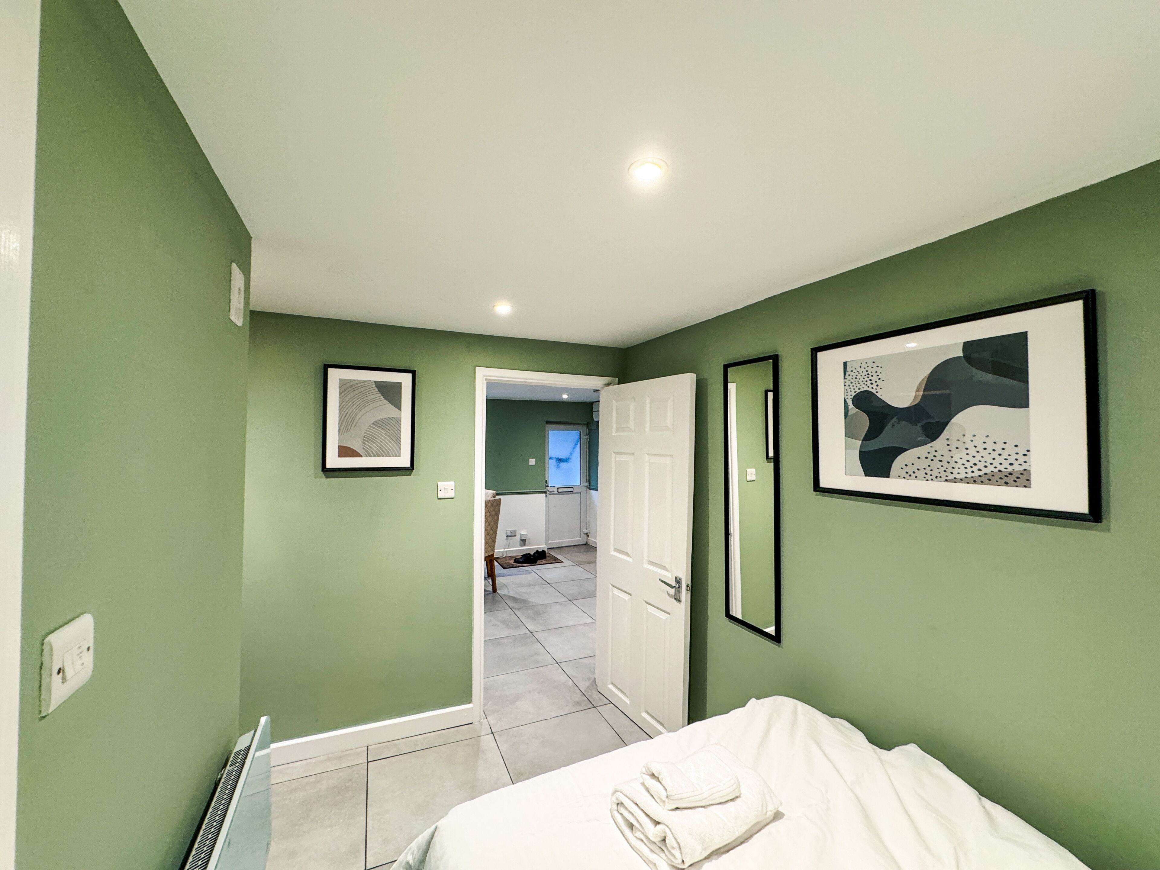A bedroom with a bed, a door leading to a bathroom, and a hallway.