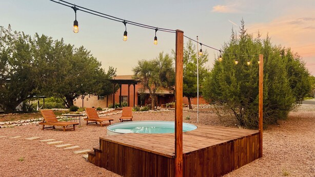 A wooden deck with a hot tub, surrounded by gravel, with a pergola and lounge chairs. - Romeo's Roadhouse with Cowboy Pool (Lake Montezuma)