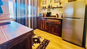 A compact kitchen with wooden cabinets, a built-in microwave, and a stainless steel refrigerator. - Romeo's Roadhouse with Cowboy Pool (Lake Montezuma)