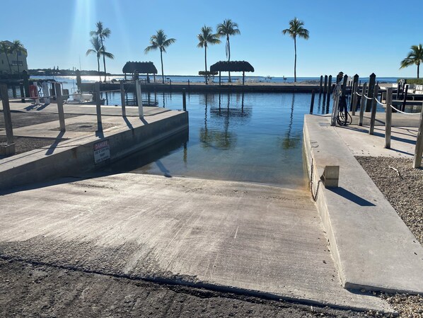 A marina with a concrete dock, palm trees, and a clear sky. - Charming Bayside 2 bed, 2 bath Condo at Futura in Islamorada WiFi, Pool, Dockage (Tavernier)