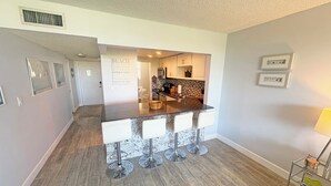 A modern kitchen with a bar area, white bar stools, and a kitchen island. - Charming Bayside 2 bed, 2 bath Condo at Futura in Islamorada WiFi, Pool, Dockage (Tavernier)