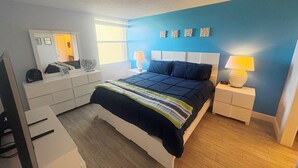 A bedroom with a bed, bedside tables, a lamp, a mirror, and a dresser. - Charming Bayside 2 bed, 2 bath Condo at Futura in Islamorada WiFi, Pool, Dockage (Tavernier)