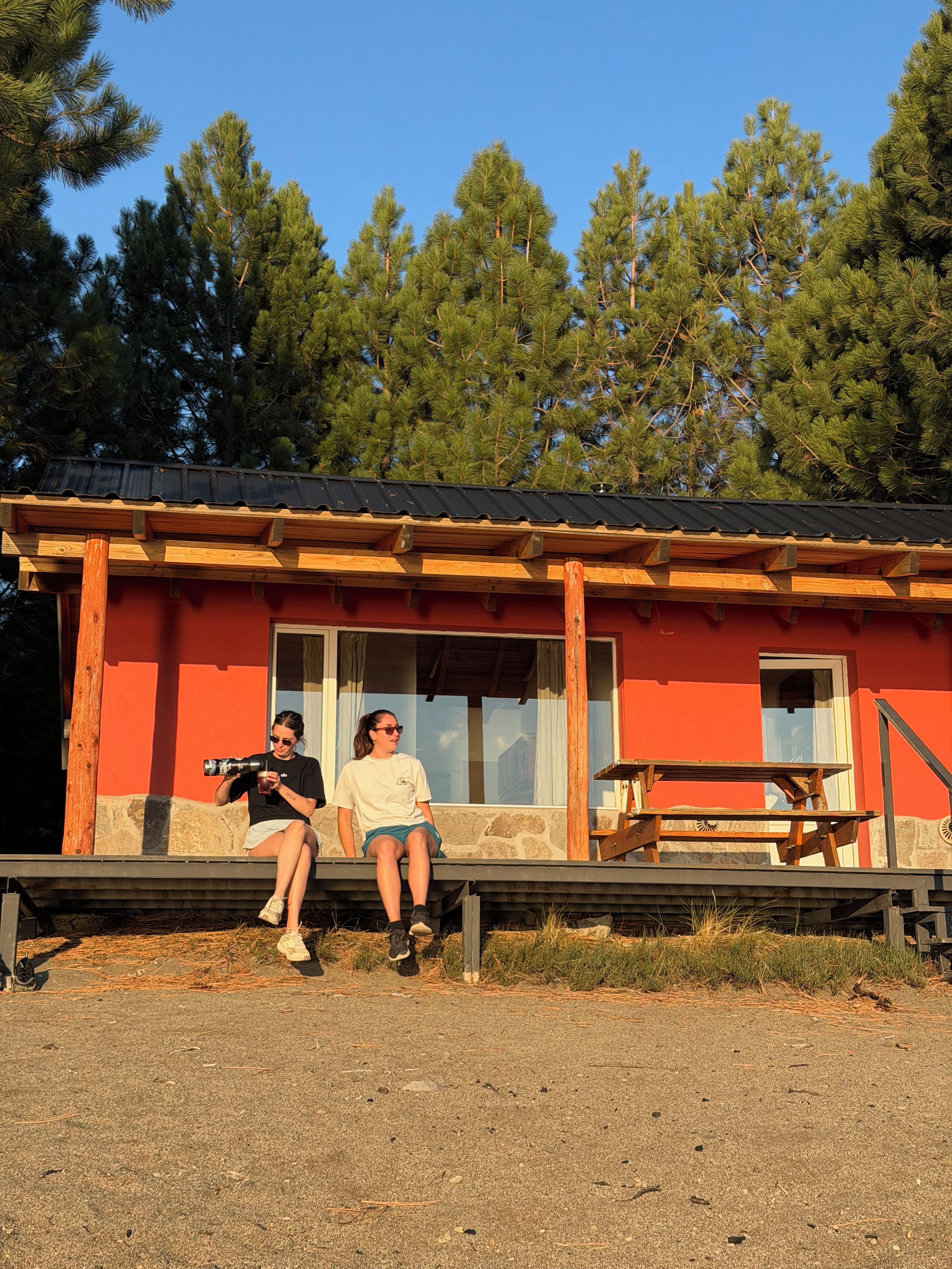 A building with a red exterior, a wooden deck, and a clear view of the surrounding trees.