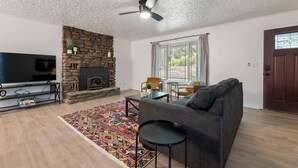 A living room with a stone fireplace, a television, a sofa, and a patterned rug. - Updated, Cozy home- minutes to Tunnel Vision Trail!  (Bella Vista)