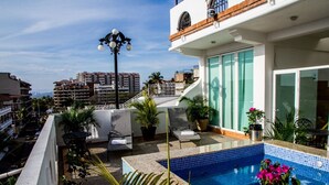 A rooftop pool area with a blue-tiled pool, lounge chairs, and potted plants. - Andales Suites 101 (Puerto Vallarta)