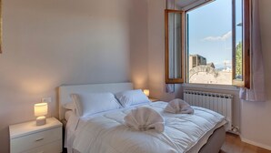 Quarto de hotel com cama, mesa de cabeceira, janela com cortinas e vista para o exterior.