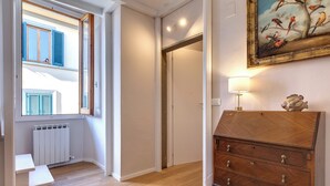 Um corredor com cômoda de madeira, um banco, radiador e um quadro na parede.