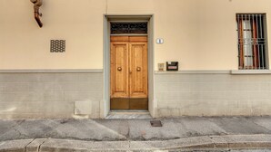 Um edifício bege com porta dupla de madeira, janela com grades e uma pequena caixa de correio.