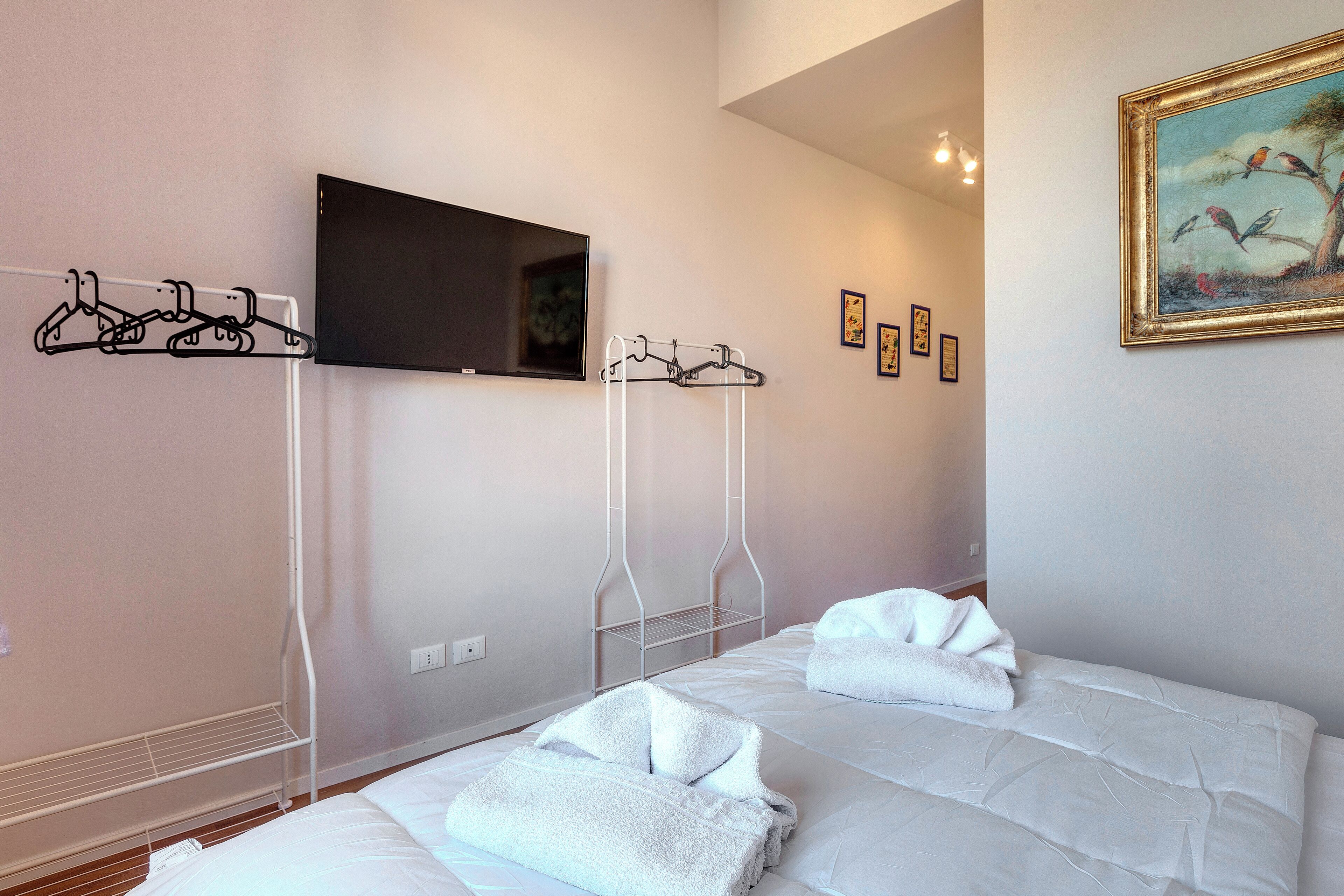 A hotel room with a bed, a TV mounted on the wall, and a painting.