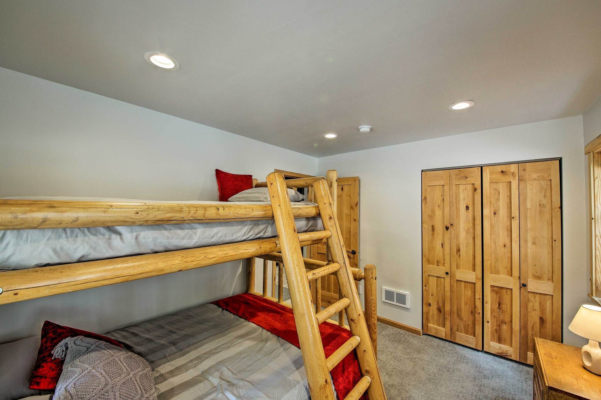 Ein Schlafraum mit Etagenbetten, einer Garderobe und einem Schreibtisch mit Lampe.