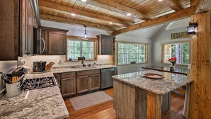 Una cocina con vigas de madera, encimeras de granito y una isla central.