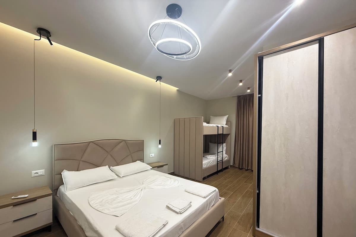 Un dormitorio moderno con una cama grande, una litera, un armario y una lámpara en el techo.