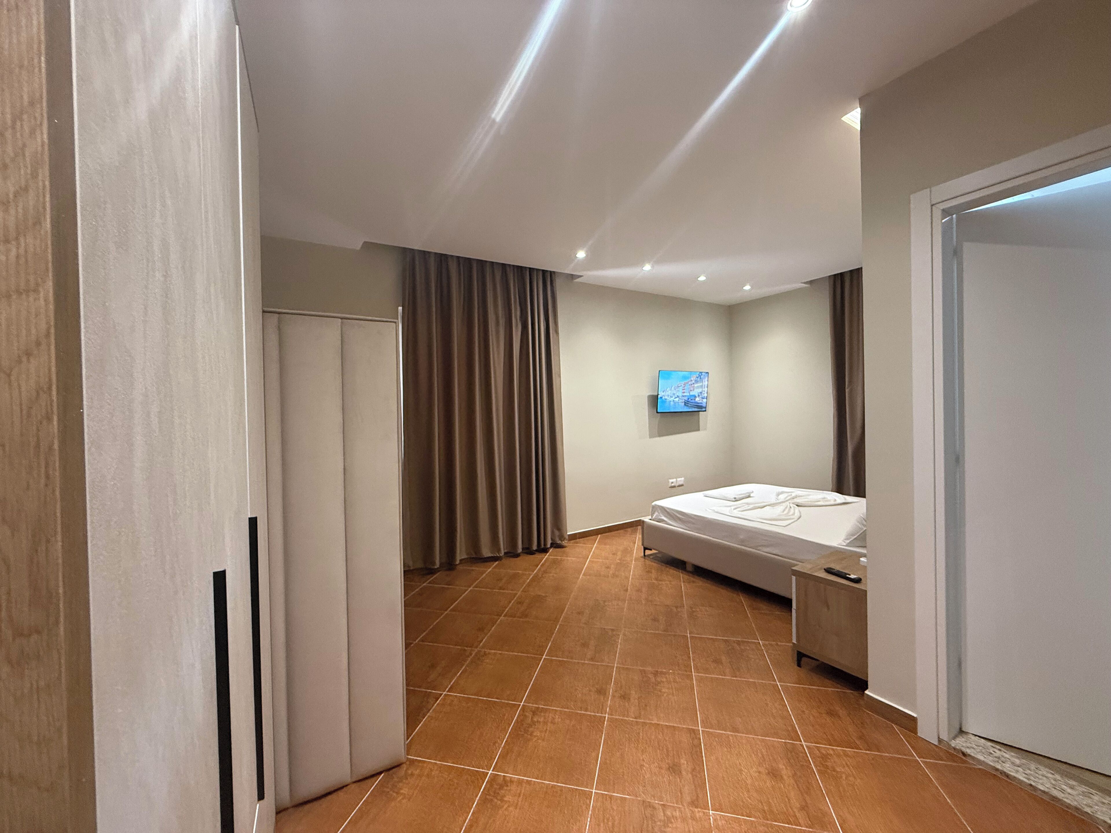 Een moderne hotelkamer met een bed, een aan de muur bevestigde televisie en een kledingkast.