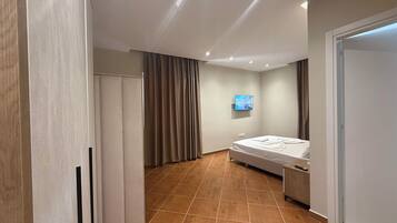 Een moderne hotelkamer met een bed, een aan de muur bevestigde televisie en een kledingkast.