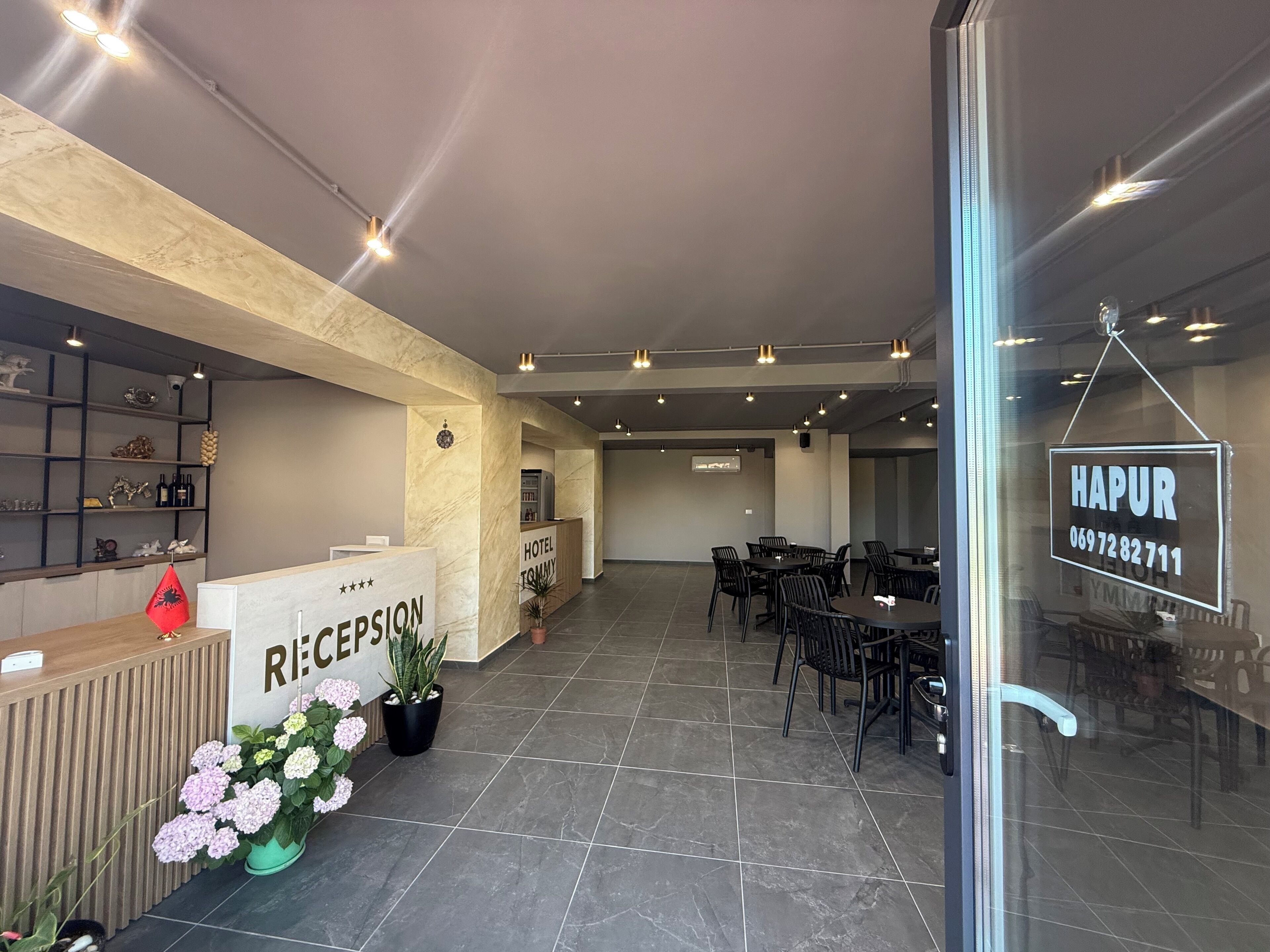 Een hotel receptie met een receptiebalie, een 'HAPUR' bord en een zithoek met tafels en stoelen.