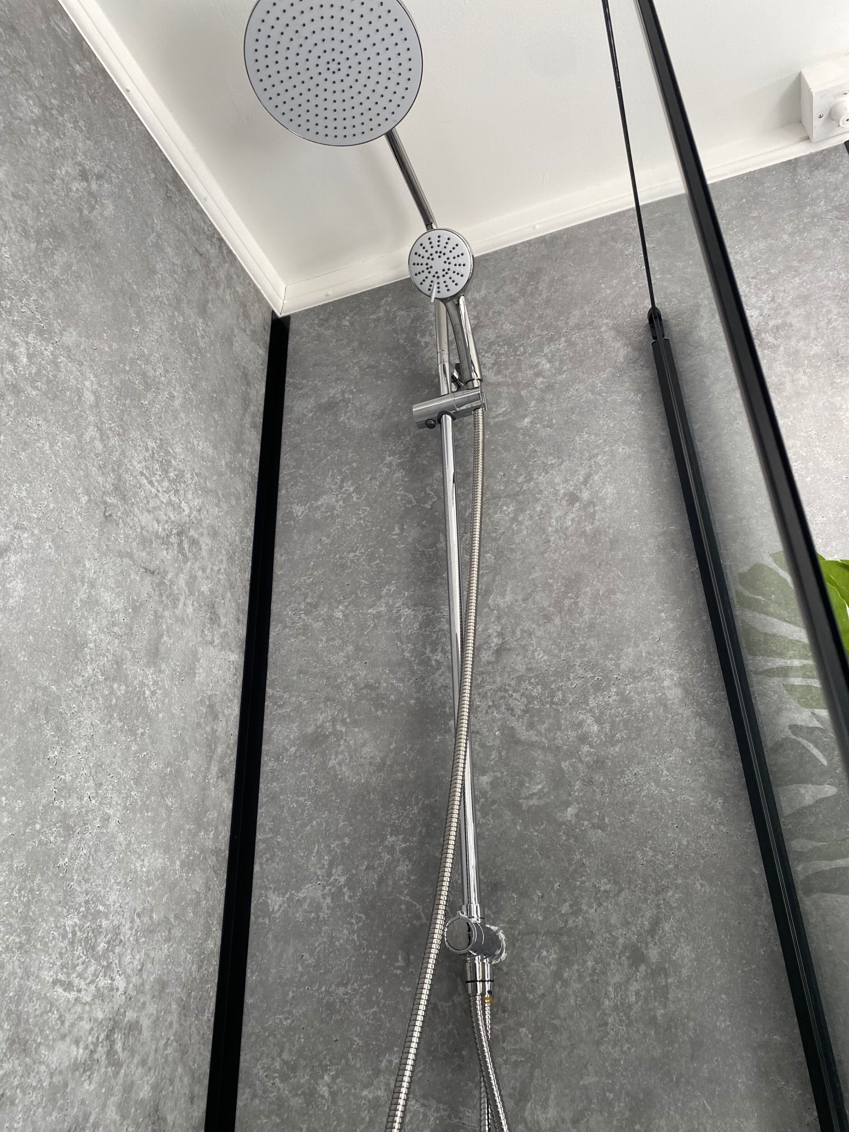 A modern shower with a handheld showerhead and multiple flexible hoses.
