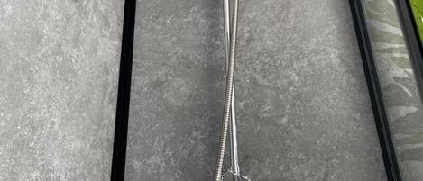 A modern shower with a handheld showerhead and multiple flexible hoses.