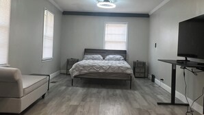 Un dormitorio con cama, televisor, escritorio y silla.