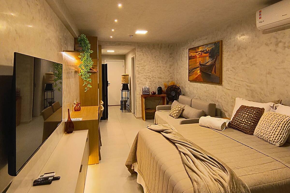 A modern bedroom with a bed, a flat-screen TV, a desk, and a chair.