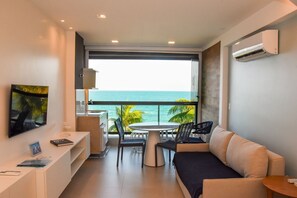 Een moderne kamer met balkon, een bank, een eettafel en een televisie.