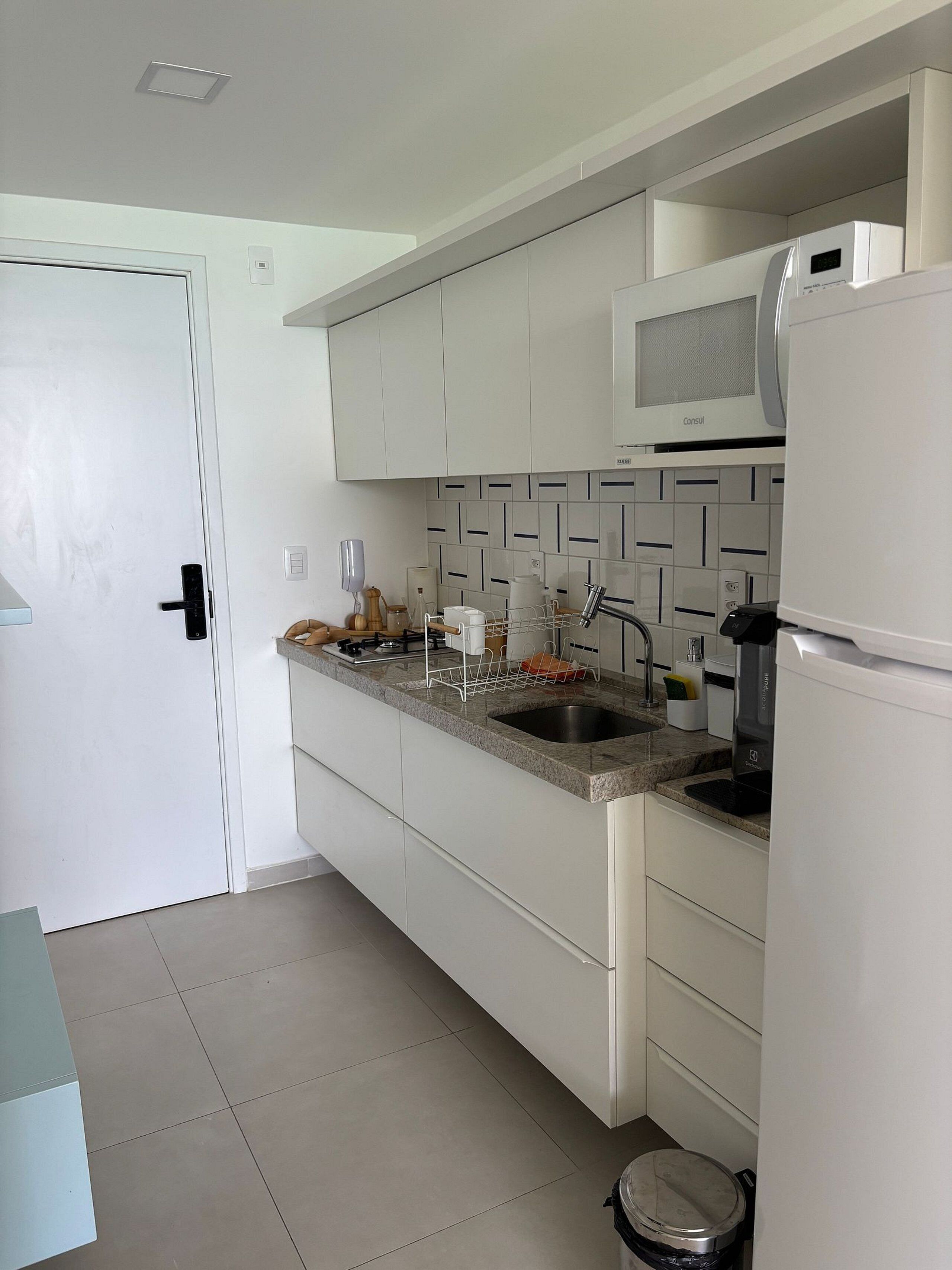 A modern kitchen with white cabinets, a granite countertop, a built-in microwave, and a stainless steel sink.