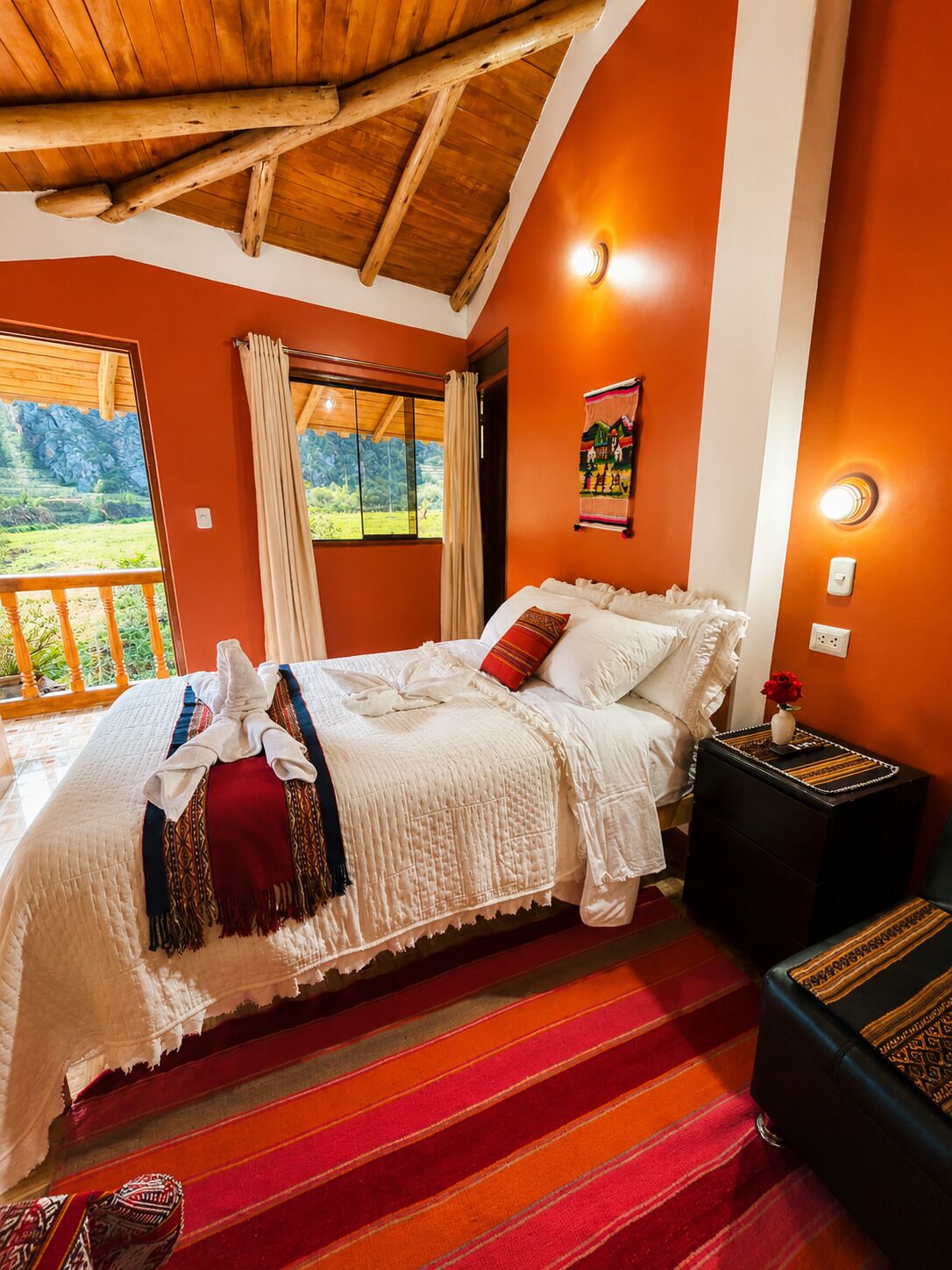 A bedroom with a bed, a nightstand, a window with curtains, and a view of greenery outside.