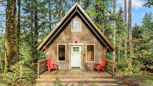Eine Holzhütte mit Veranda, zwei roten Stühlen und einer Tür.