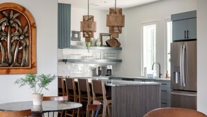 Uma cozinha moderna com uma ilha central, cadeiras de madeira e lustres de vime suspensos.