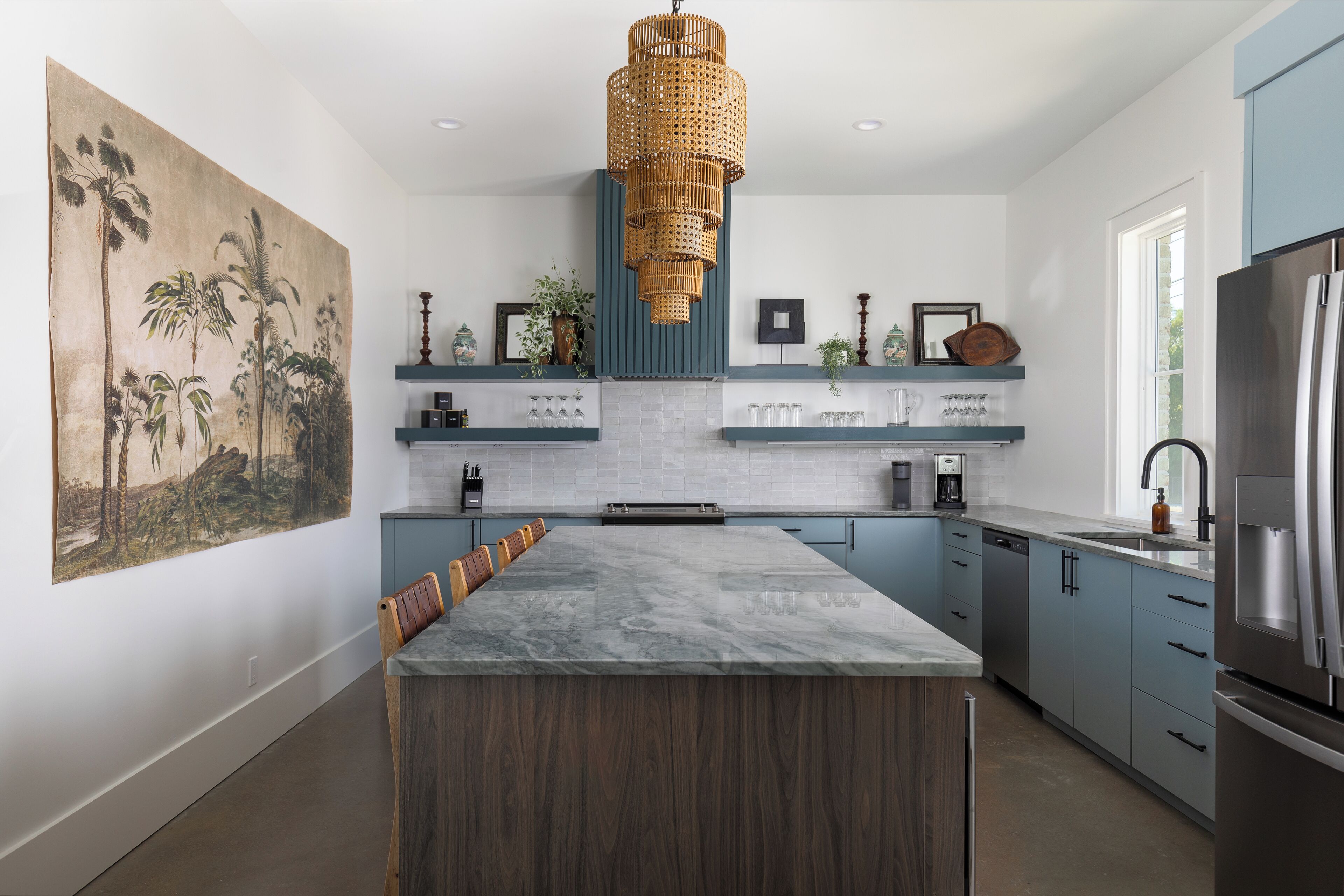 A modern kitchen with a large island, blue cabinets, and a hanging light fixture.