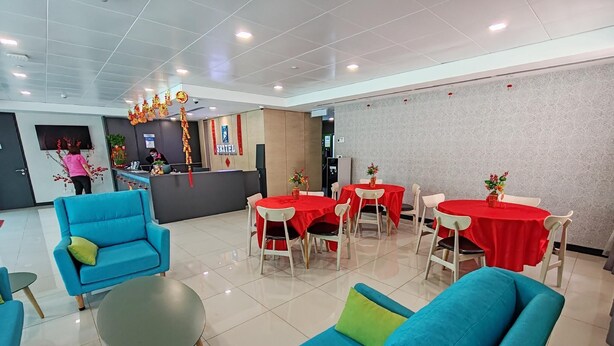 A hotel lobby with blue sofas, red tables, and a reception desk. - Sritel Boutique Hotel (Shah Alam)