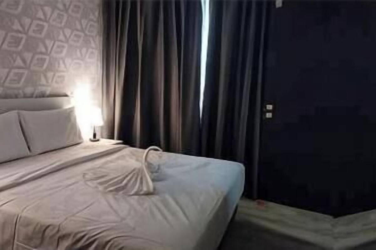 Ein Hotelzimmer mit zwei Betten, einer dunklen Tür und einer Wand mit Muster.