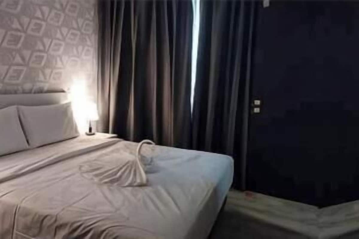 A hotel room with two beds, a dark door, and a patterned wall.